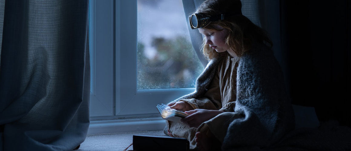 Enfant qui écrit dans un journal intime près de sa fenêtre avec une lampe sur la tête